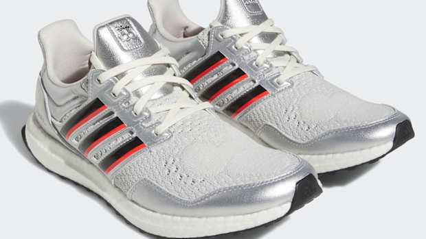 View of silver, black, and red adidas shoes.